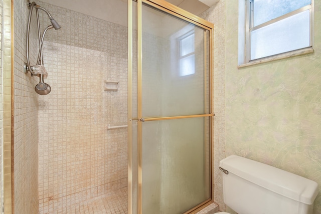 bathroom with plenty of natural light, a stall shower, toilet, and wallpapered walls