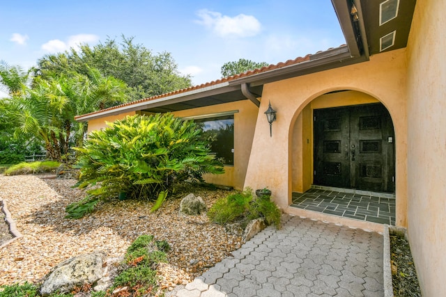 view of exterior entry featuring stucco siding and a tile roof