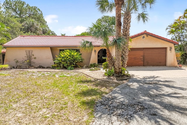 mediterranean / spanish house with stucco siding, driveway, a tile roof, and a garage