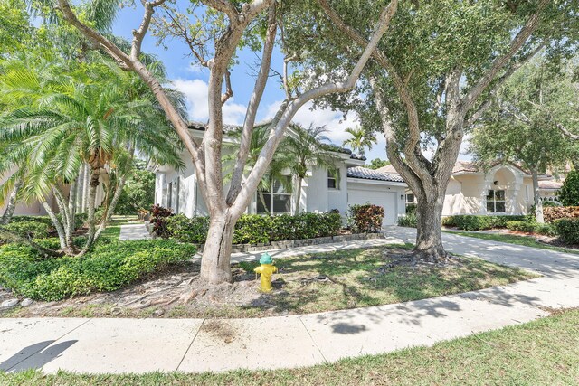 7793 Highlands Cir, Margate, FL 33063 - view of front of house featuring an attached garage, concrete driveway, a tiled roof, and stucco siding