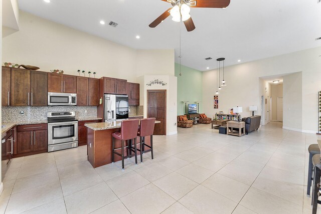 7793 Highlands Cir, Margate, FL 33063 - kitchen with appliances with stainless steel finishes, a high ceiling, backsplash, ceiling fan, and a center island