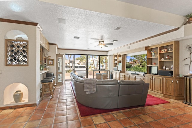 living area featuring a textured ceiling, healthy amount of natural light, ceiling fan, and crown molding
