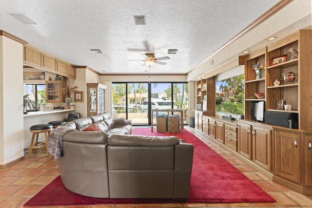 living room featuring ceiling fan, crown molding, light tile patterned floors, and a textured ceiling