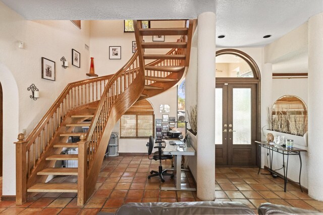 entryway featuring stairway, french doors, arched walkways, and baseboards