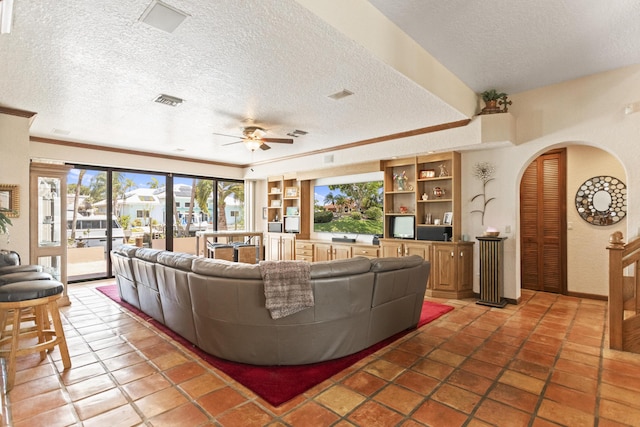 living room featuring a textured ceiling, ceiling fan, plenty of natural light, arched walkways, and ornamental molding