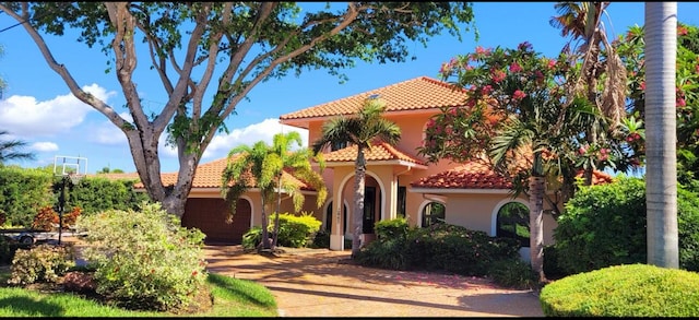 mediterranean / spanish-style house with a tile roof, stucco siding, a garage, and driveway
