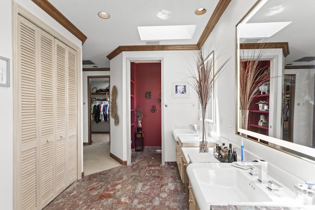 bathroom featuring a closet, a skylight, vanity, recessed lighting, and baseboards