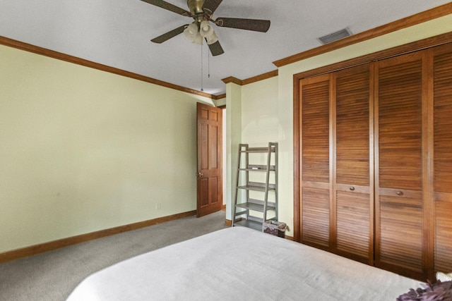 carpeted bedroom with baseboards, crown molding, a closet, and a ceiling fan