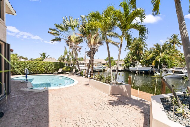 view of pool with a patio, a water view, and a boat dock