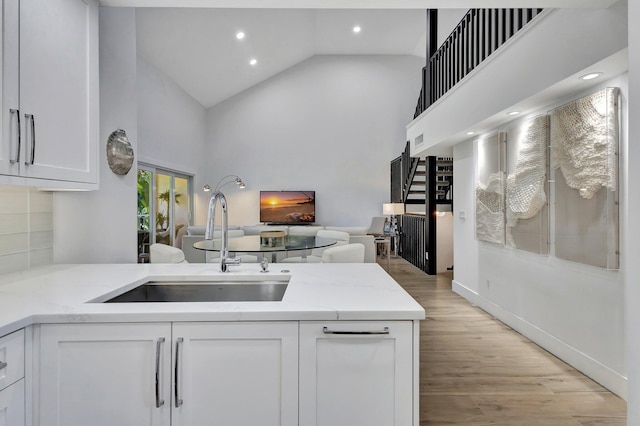 3704 Fairway Dr N, Jupiter, FL 33477 - kitchen with a sink, high vaulted ceiling, white cabinets, open floor plan, and light stone counters