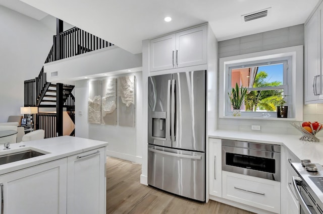 3704 Fairway Dr N, Jupiter, FL 33477 - kitchen with stainless steel refrigerator with ice dispenser, white cabinets, light wood-style flooring, light countertops, and recessed lighting