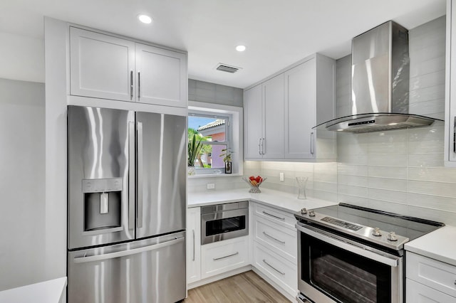 3704 Fairway Dr N, Jupiter, FL 33477 - kitchen with stainless steel appliances, wall chimney exhaust hood, light countertops, backsplash, and white cabinets