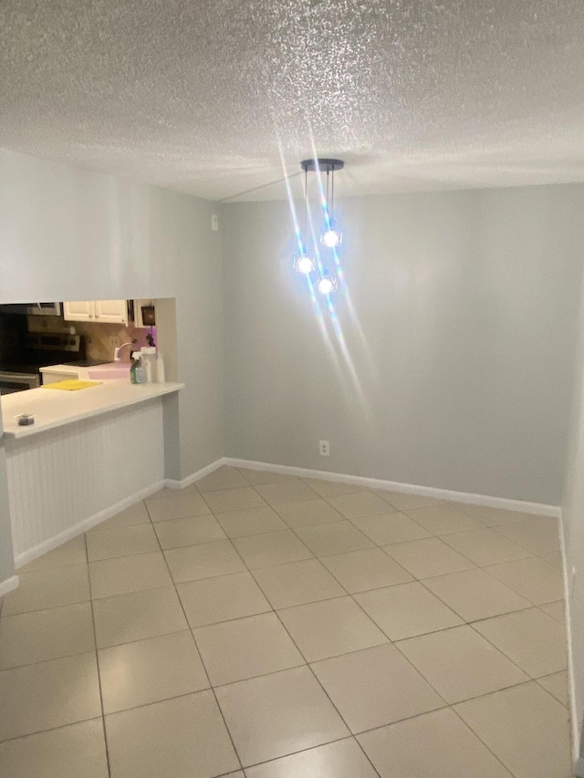 719 Sunny Pine Way Unit G1, Greenacres, FL 33415 - unfurnished dining area featuring a textured ceiling, light tile patterned floors, and baseboards