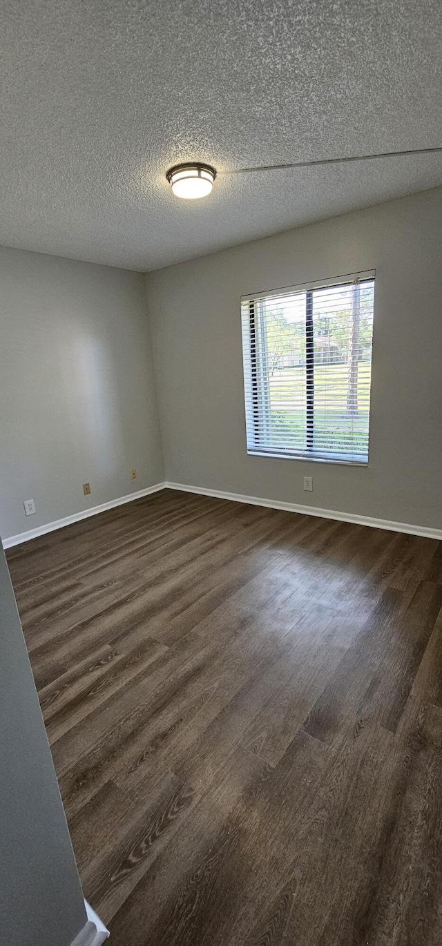 spare room with dark wood-style floors, baseboards, and a textured ceiling