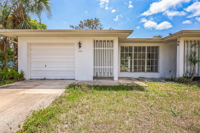 view of front of home with stucco siding, a garage, concrete driveway, and a front lawn