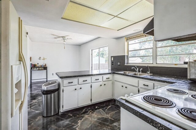 kitchen featuring white fridge with ice dispenser, dark marble finish flooring, a peninsula, range, and dark countertops