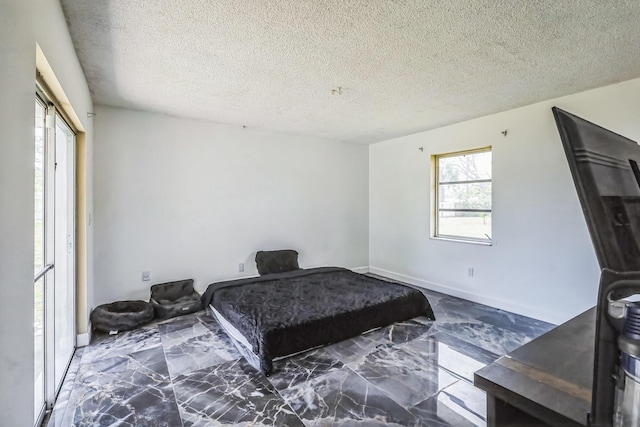 bedroom with marble finish floors and a textured ceiling