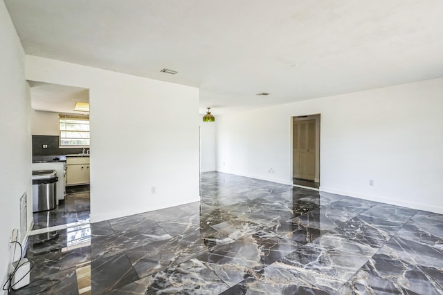 empty room featuring dark marble finish floors and baseboards