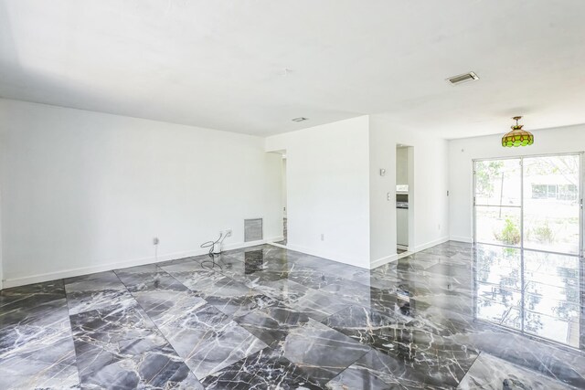empty room featuring marble tiled floors and baseboards
