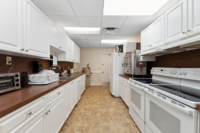 2520 Black Olive Blvd Unit 103, Delray Beach, FL 33445 - kitchen featuring a sink, white appliances, dark countertops, white cabinetry, and a paneled ceiling