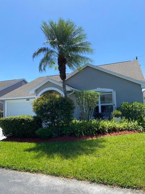 378 NW Sherry Ln, Port Saint Lucie, FL 34986 - view of side of home with an attached garage, a yard, stucco siding, and roof with shingles