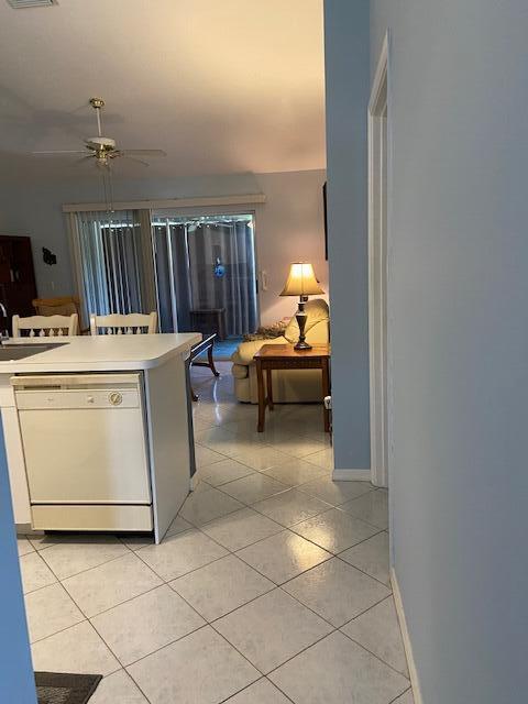 378 NW Sherry Ln, Port Saint Lucie, FL 34986 - kitchen with white dishwasher, light tile patterned flooring, ceiling fan, light countertops, and baseboards
