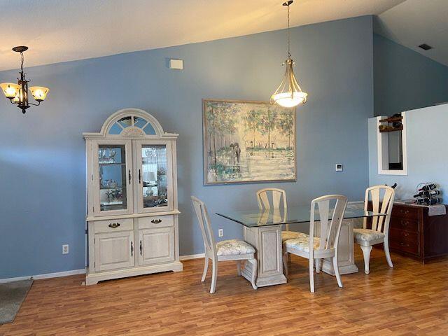 378 NW Sherry Ln, Port Saint Lucie, FL 34986 - dining space featuring a chandelier, wood finished floors, high vaulted ceiling, and baseboards