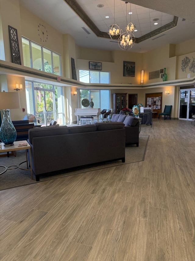 378 NW Sherry Ln, Port Saint Lucie, FL 34986 - living area featuring a towering ceiling, a tray ceiling, a chandelier, wood finished floors, and recessed lighting