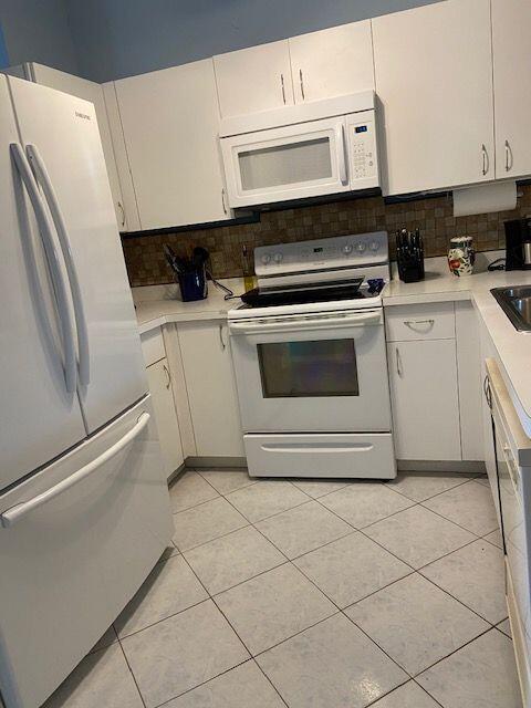 378 NW Sherry Ln, Port Saint Lucie, FL 34986 - kitchen with white appliances, light countertops, light tile patterned floors, and white cabinets
