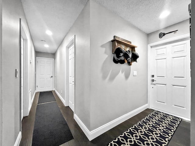 corridor featuring a textured ceiling, baseboards, dark wood-style floors, and recessed lighting