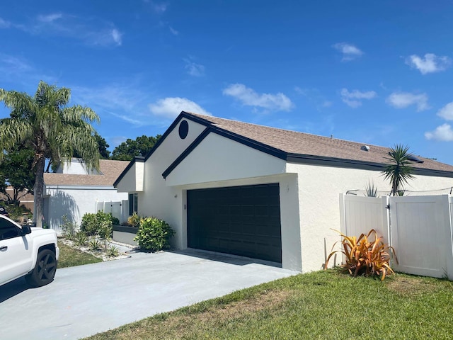 view of front of house featuring a garage, stucco siding, driveway, and fence