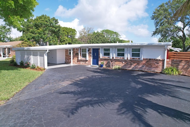 825 Northern Dr, Lake Park, FL 33403 - ranch-style home with driveway, brick siding, a carport, and a front lawn