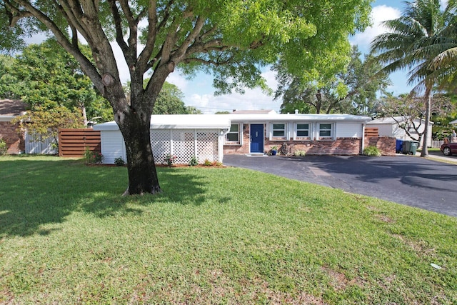825 Northern Dr, Lake Park, FL 33403 - view of front of house with brick siding, a front yard, and driveway