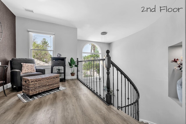 living area featuring wood finished floors, baseboards, and an upstairs landing