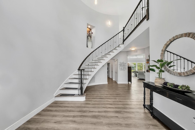 stairs with baseboards, a high ceiling, and wood finished floors