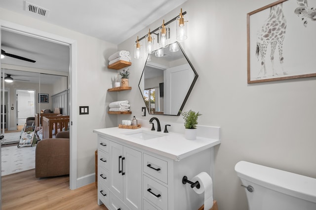 6824 68th Way, West Palm Beach, FL 33409 - bathroom featuring toilet, wood finished floors, vanity, baseboards, and ceiling fan