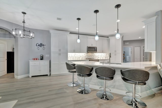 1236 SE Conference Cir, Stuart, FL 34997 - kitchen with stainless steel microwave, light countertops, white cabinets, a breakfast bar, and recessed lighting