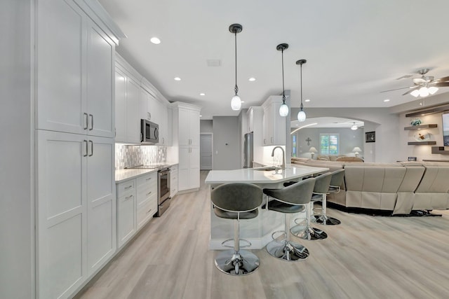1236 SE Conference Cir, Stuart, FL 34997 - kitchen featuring appliances with stainless steel finishes, a ceiling fan, open floor plan, light wood-style floors, and a breakfast bar area