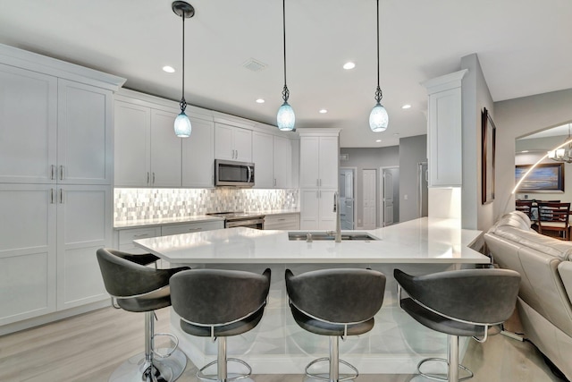 1236 SE Conference Cir, Stuart, FL 34997 - kitchen featuring stainless steel appliances, a kitchen bar, light countertops, decorative backsplash, and recessed lighting