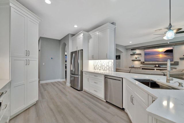 1236 SE Conference Cir, Stuart, FL 34997 - kitchen featuring appliances with stainless steel finishes, arched walkways, ceiling fan, open floor plan, and light wood-type flooring