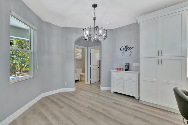 1236 SE Conference Cir, Stuart, FL 34997 - dining room with arched walkways, a chandelier, and light wood-style flooring