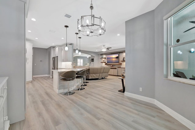 1236 SE Conference Cir, Stuart, FL 34997 - kitchen with a breakfast bar, a ceiling fan, white cabinets, open floor plan, and freestanding refrigerator