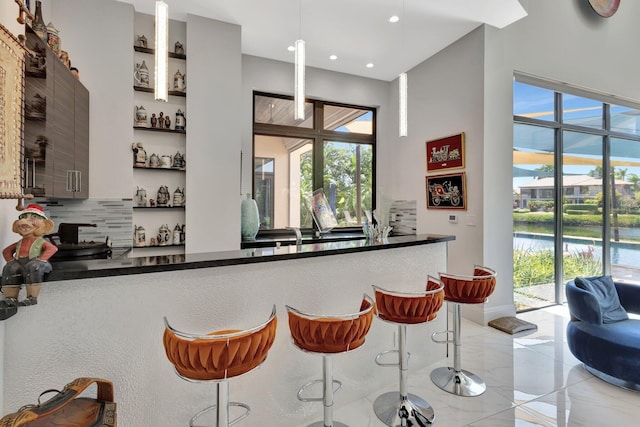 2783 Rhone Dr, Palm Beach Gardens, FL 33410 - bar area featuring healthy amount of natural light, recessed lighting, tasteful backsplash, and light marble finish floors
