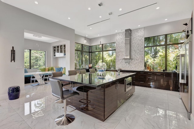 2783 Rhone Dr, Palm Beach Gardens, FL 33410 - kitchen featuring modern cabinets, wall chimney range hood, light marble finish flooring, stainless steel microwave, and a large island