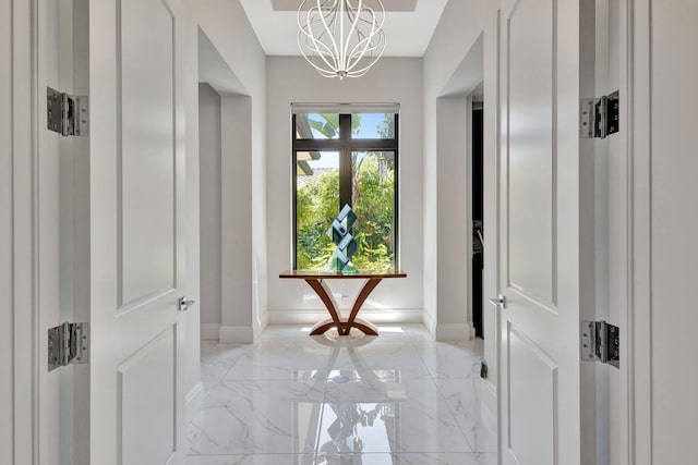 2783 Rhone Dr, Palm Beach Gardens, FL 33410 - hallway featuring light marble finish flooring, a chandelier, and baseboards