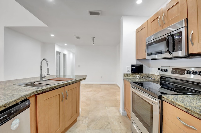 kitchen featuring stainless steel appliances, a sink, light brown cabinetry, recessed lighting, and baseboards