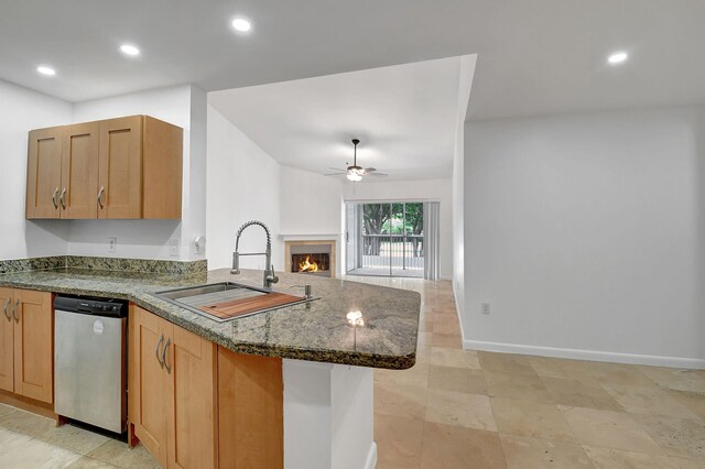 kitchen with dishwasher, a sink, ceiling fan, a warm lit fireplace, and a peninsula
