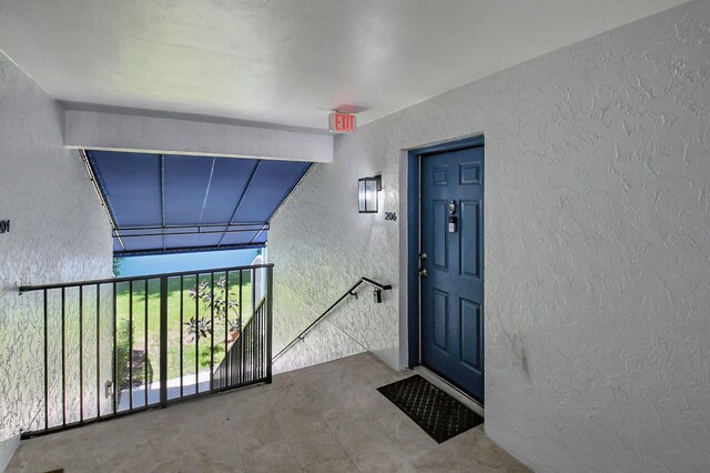 view of exterior entry featuring stucco siding and a balcony