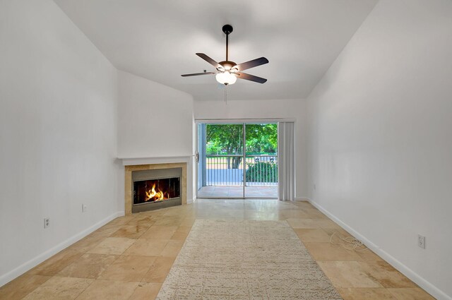 unfurnished living room with a fireplace, ceiling fan, and baseboards