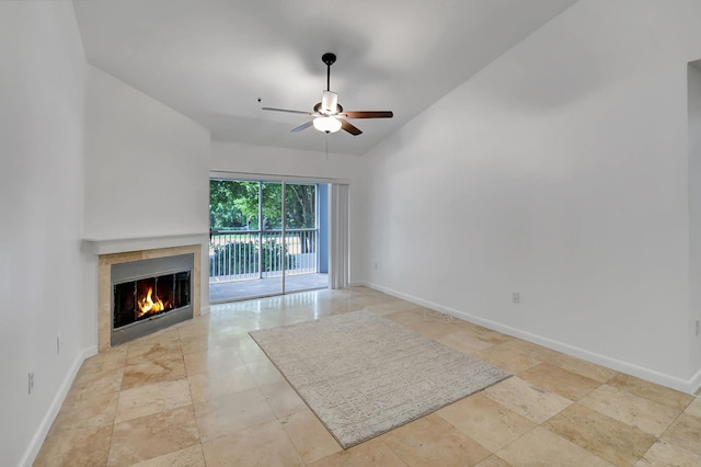 unfurnished living room featuring ceiling fan, a glass covered fireplace, and baseboards